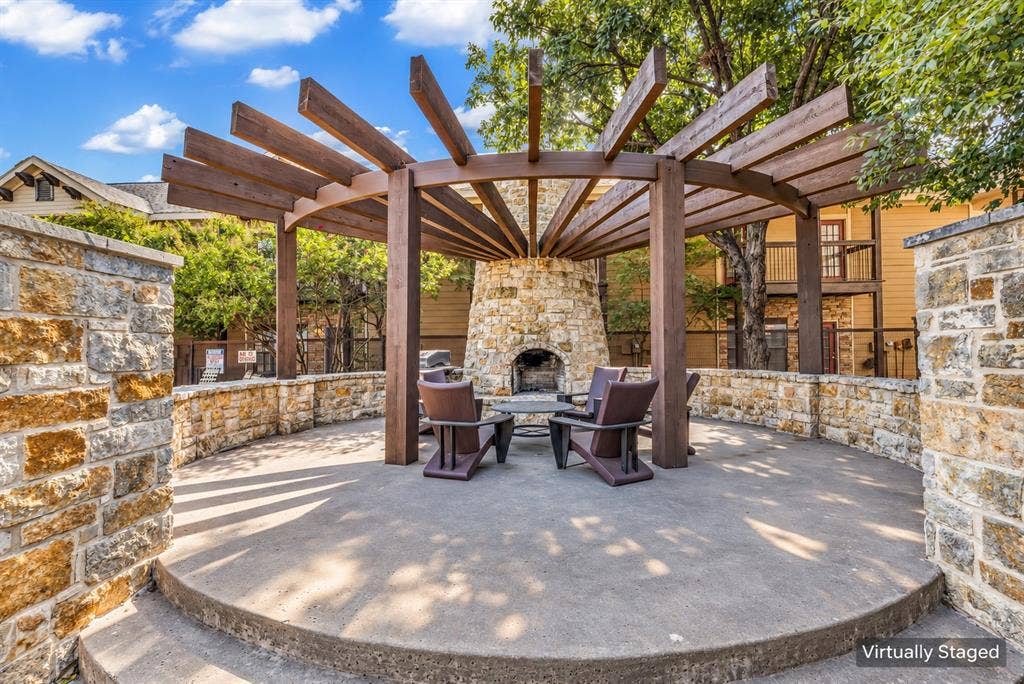 2410 S 2nd Street, #625, Waco, TX 76706 Outdoor patio featuring a circular stone masonry fireplace, a wooden pergola, and stone perimeter walls