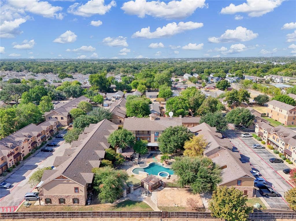 2410 S 2nd Street, #625, Waco, TX 76706 Aerial perspective of multi-family residential complex featuring a swimming pool, attached spa, wooden pergola, and paved parking surfaces