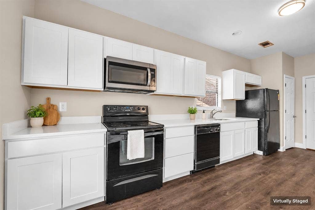 2410 S 2nd Street, #625, Waco, TX 76706 Kitchen featuring white shaker-style cabinetry, solid-surface countertops, wood-finish flooring, and black appliances
