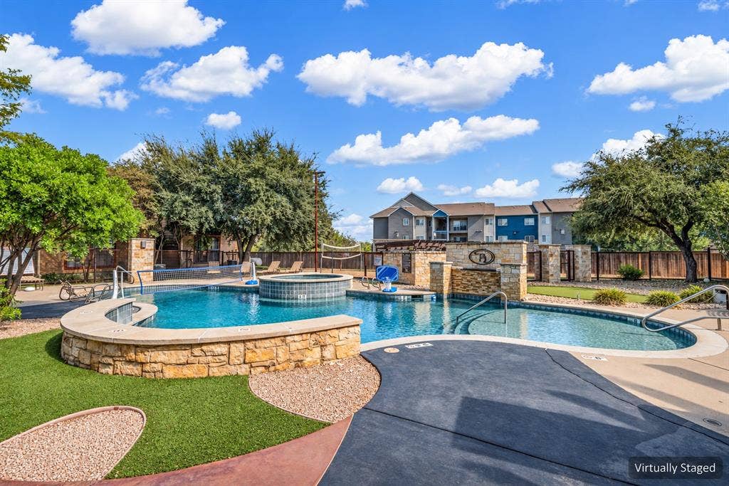 2410 S 2nd Street, #625, Waco, TX 76706 Swimming pool featuring stone-clad retaining walls, an integrated hot tub, a built-in water feature, and a concrete deck