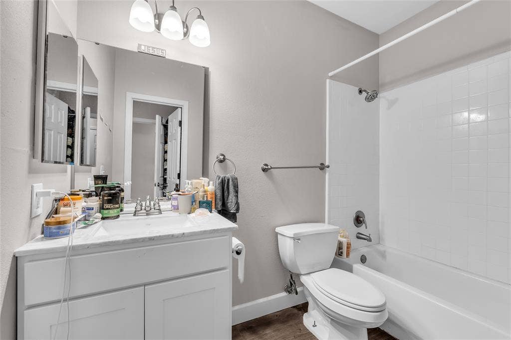 2410 S 2nd Street, #625, Waco, TX 76706 Bathroom featuring a white vanity with a stone countertop, an undermount sink, a framed wall mirror, a three-light fixture, and a tub-shower combination with white wall tile
