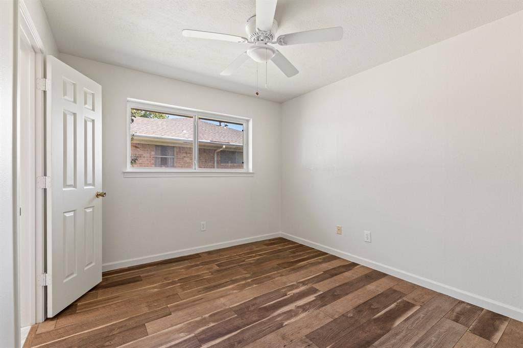 8406 Lullwater Drive, Dallas, TX 75218 Room featuring wood-finish flooring, a white-paneled interior door, and a ceiling-mounted fan with integrated lighting