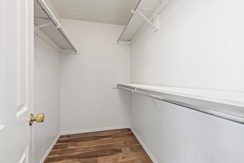 8406 Lullwater Drive, Dallas, TX 75218 Storage space featuring wood-finish flooring, metal hanging rods, and built-in shelving