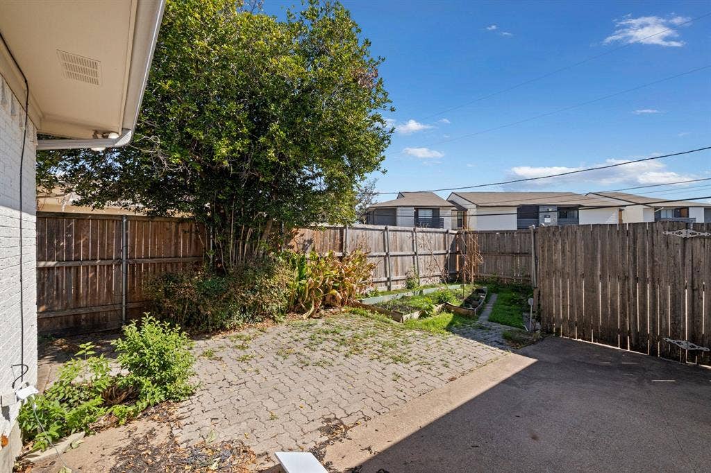 8406 Lullwater Drive, Dallas, TX 75218 Backyard featuring a paved patio, wood privacy fencing, mature trees, and designated gardening areas