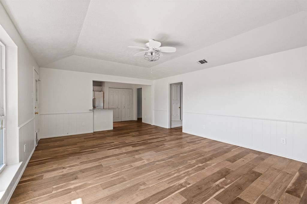 8406 Lullwater Drive, Dallas, TX 75218 Living area featuring wood-finish flooring, vaulted ceiling with a central paddle fan, wainscoting, and a breakfast bar