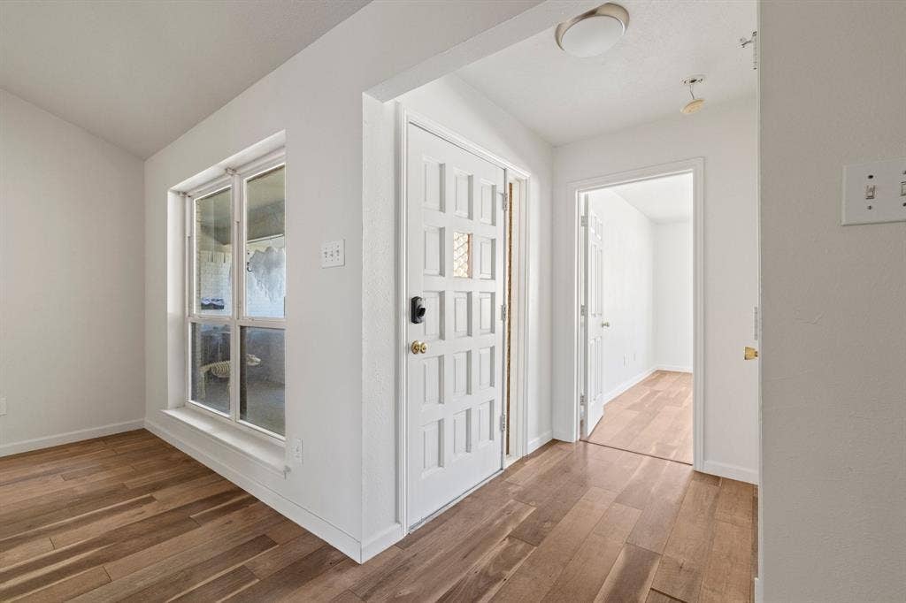 8406 Lullwater Drive, Dallas, TX 75218 Interior featuring wood-finish flooring, white walls, paneled exterior entry door, and multi-pane window