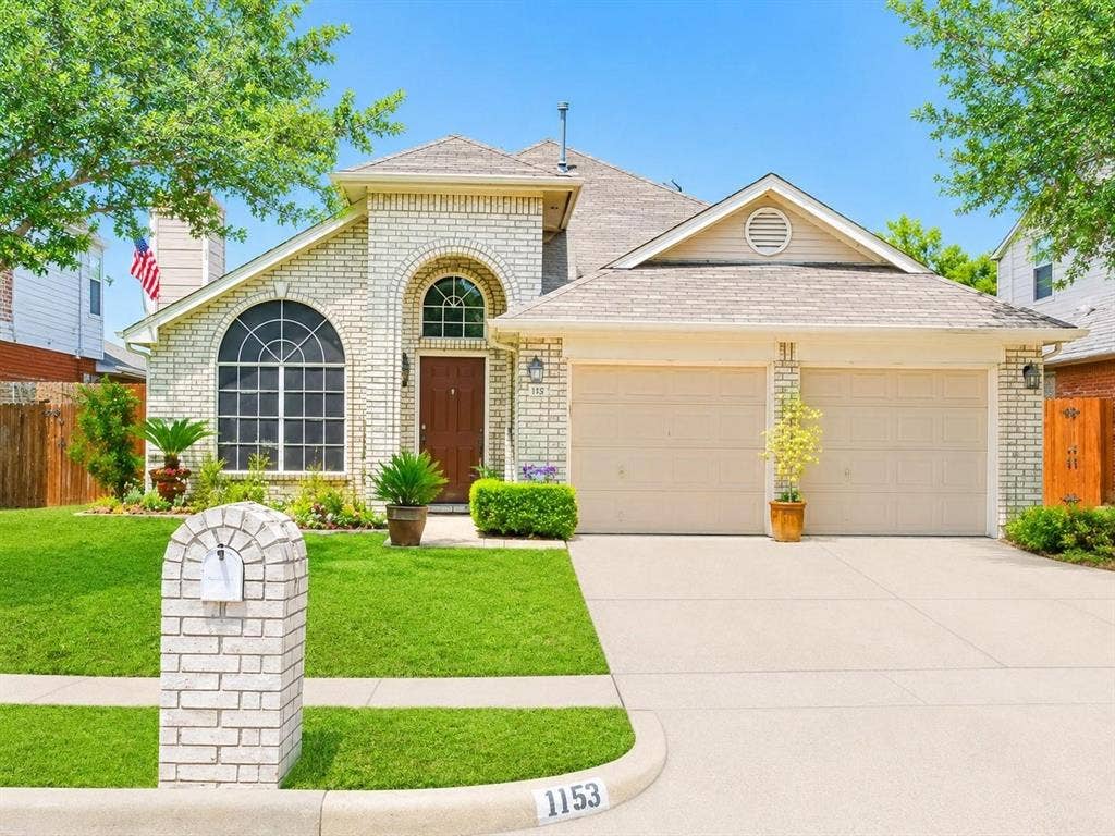 Single-story brick exterior featuring a multi-gabled roofline, arched window detailing, two-car garage, and masonry-clad mailbox