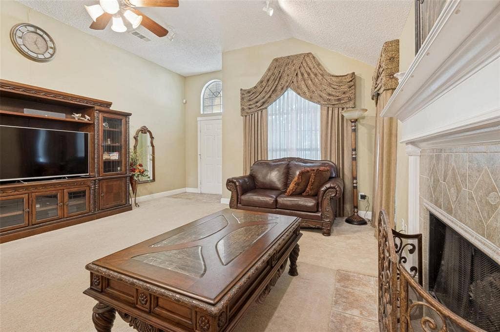Vaulted ceilings, built-in wooden cabinetry, arched window detailing, and a fireplace with tile surround