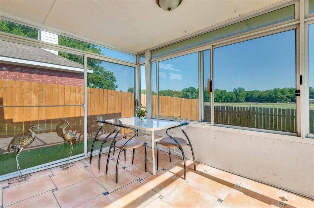 Enclosed sunroom featuring large-pane sliding glass windows, ceramic tile flooring, and a ceiling-mounted light fixture