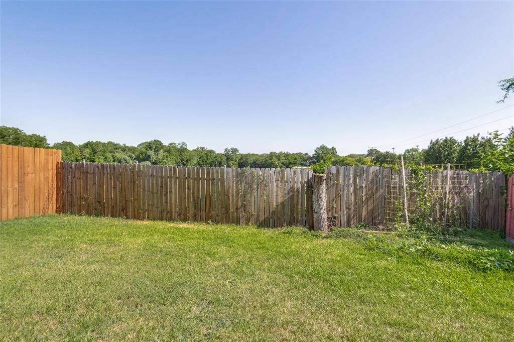 Fenced backyard featuring a grass lawn and wood picket privacy fencing