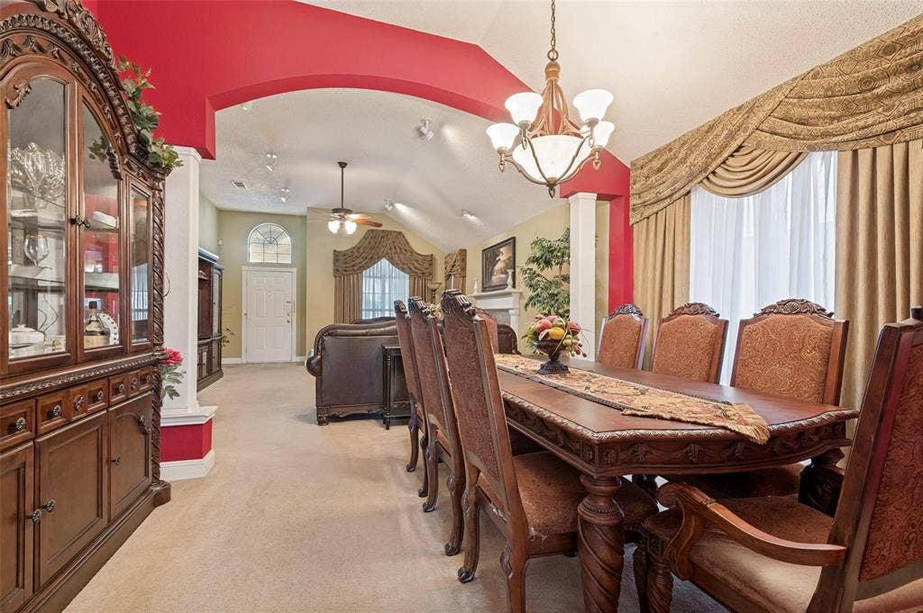 Vaulted ceilings, arched architectural detailing, multi-arm chandelier, and oversized windows