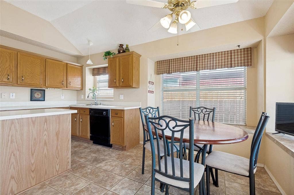 Kitchen featuring wood cabinetry, tile flooring, vaulted ceilings, and a built-in peninsula with a breakfast nook