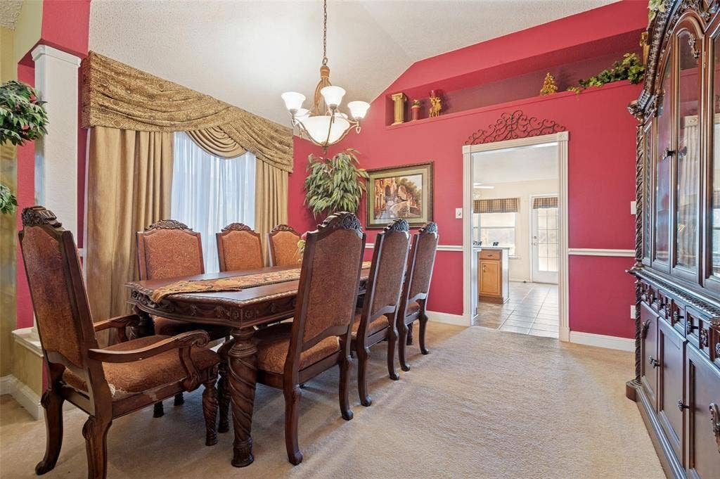 Vaulted ceiling featuring a central chandelier, decorative wall niche, and chair rail molding