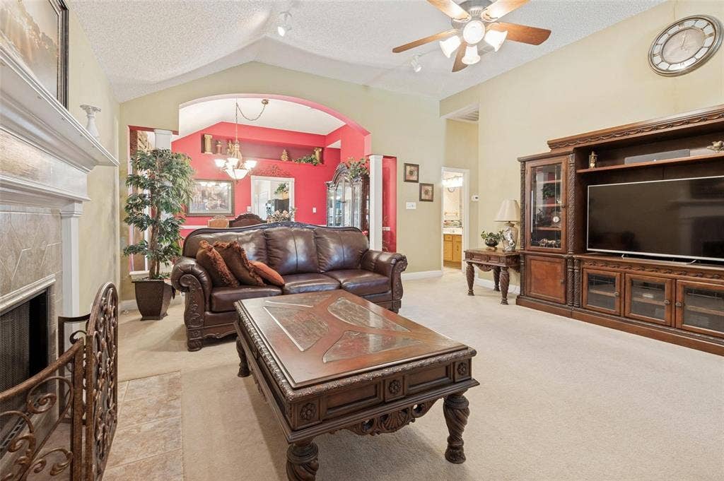 Living area featuring a vaulted ceiling, floor-to-ceiling stone-surround fireplace, and large built-in media cabinetry