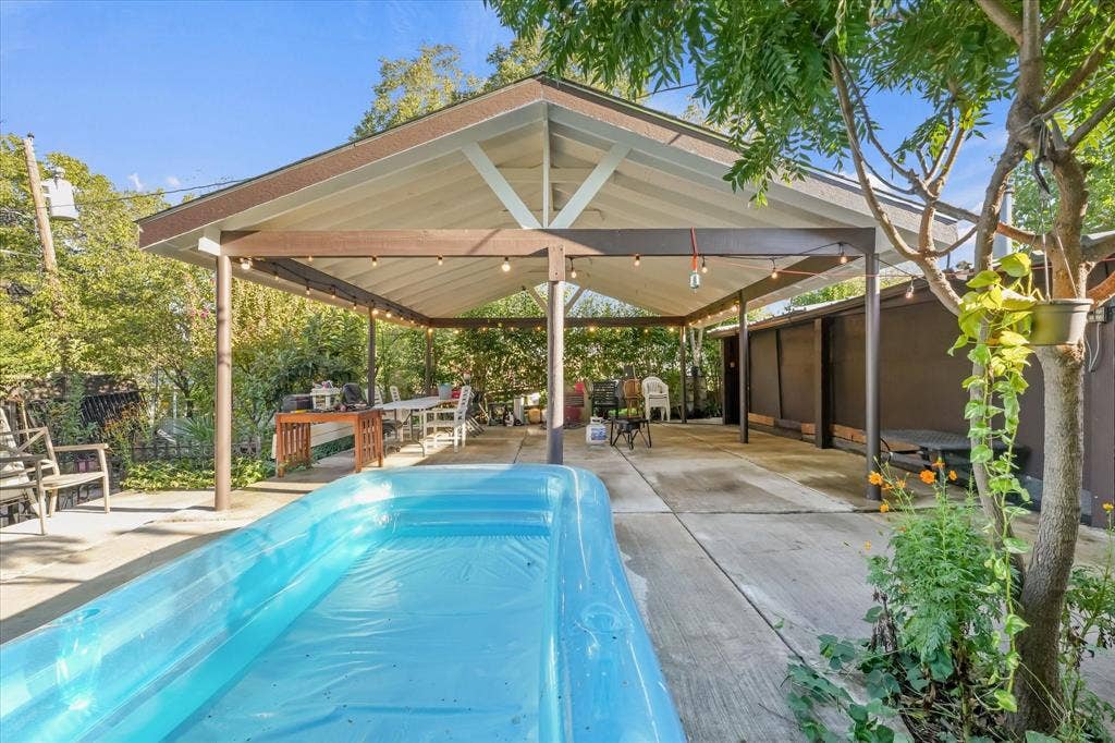 201 Glenridge Drive, Mesquite, TX 75149 Covered outdoor patio with a gable roofline, exposed wooden support beams, concrete flooring, and attached string lighting