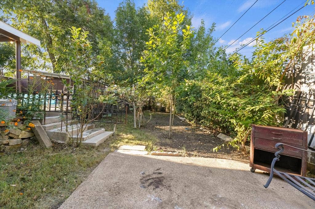 201 Glenridge Drive, Mesquite, TX 75149 Concrete patio with stone retaining wall, decorative metal railing, and mature trees