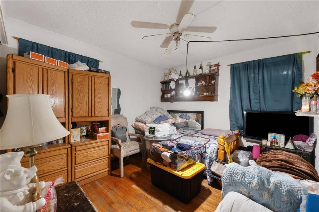 201 Glenridge Drive, Mesquite, TX 75149 Room featuring wood-finish flooring, built-in wooden cabinetry, a wall-mounted wooden display shelf, and a ceiling fan with light fixture