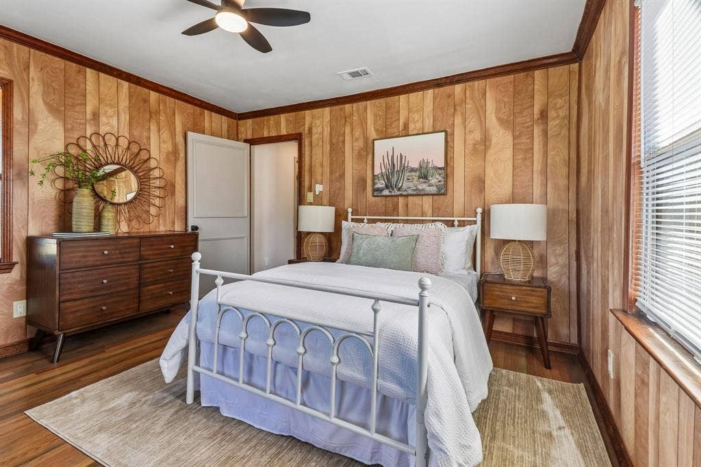 Wood paneling, wood-finish flooring, ceiling fan, white trim, and a white interior door