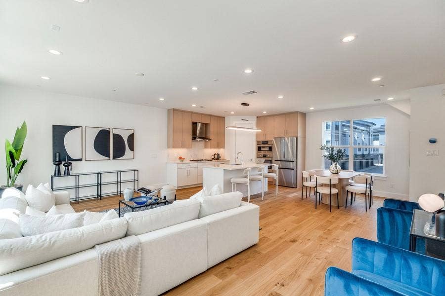 Open-concept interior featuring wood-finish flooring, recessed lighting, and a kitchen equipped with light wood-finish cabinetry, a central island, and stainless steel appliances