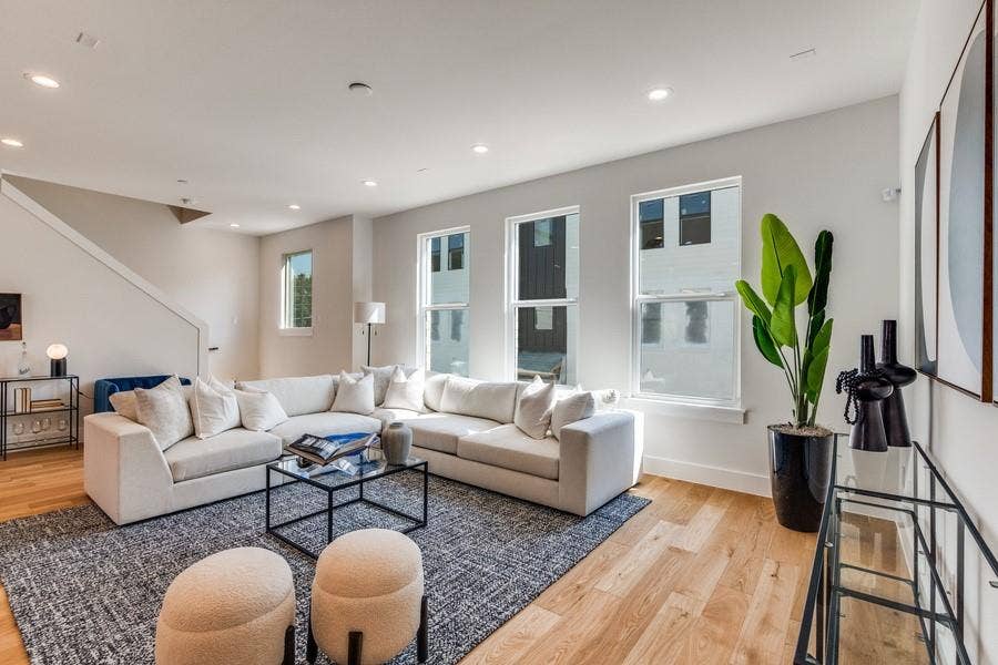 Open-concept interior featuring light wood-finish flooring, recessed lighting, and three tall vertical windows