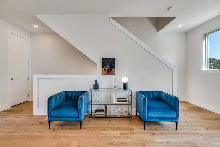 Open floor plan interior featuring wood-finish flooring, recessed lighting, a custom staircase partition with a low-profile wall, and a large window