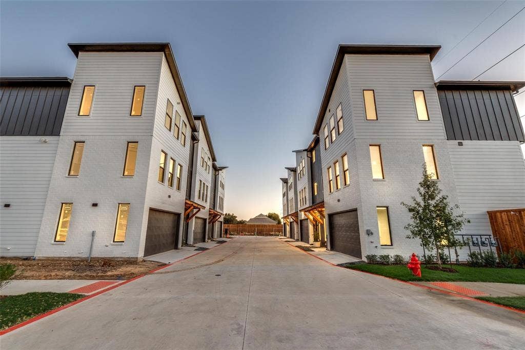 Contemporary multi-level exterior featuring horizontal lap siding, metal accents, attached garages, and large rectangular windows