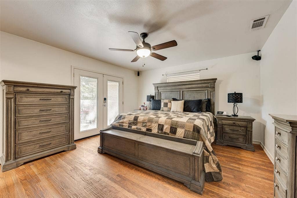 Wood-finish flooring, ceiling fan with integrated lighting, and glass-paneled double doors