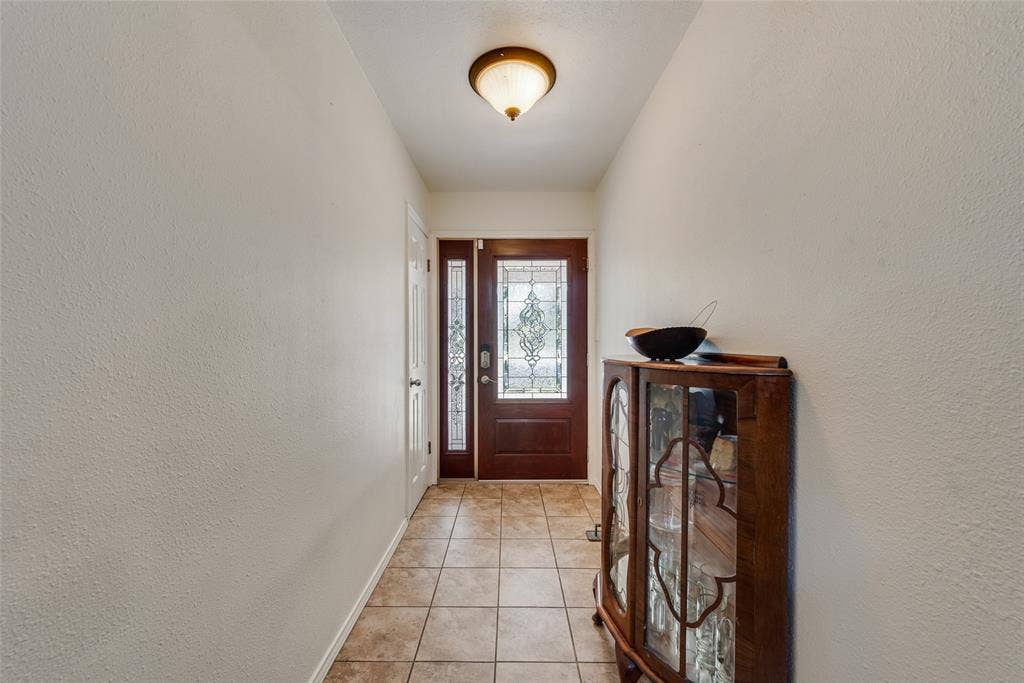 Entryway featuring tile flooring, a stained wood entry door with decorative glass inlay, a matching sidelight, and a flush-mount ceiling fixture