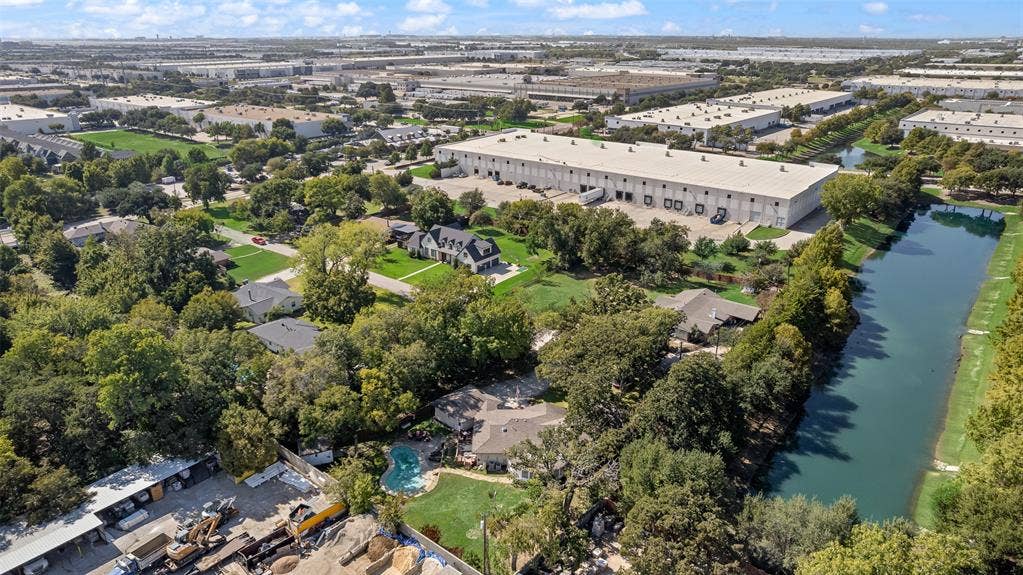 Aerial perspective featuring a lot with a backyard swimming pool, mature canopy trees, and waterfront access to a pond