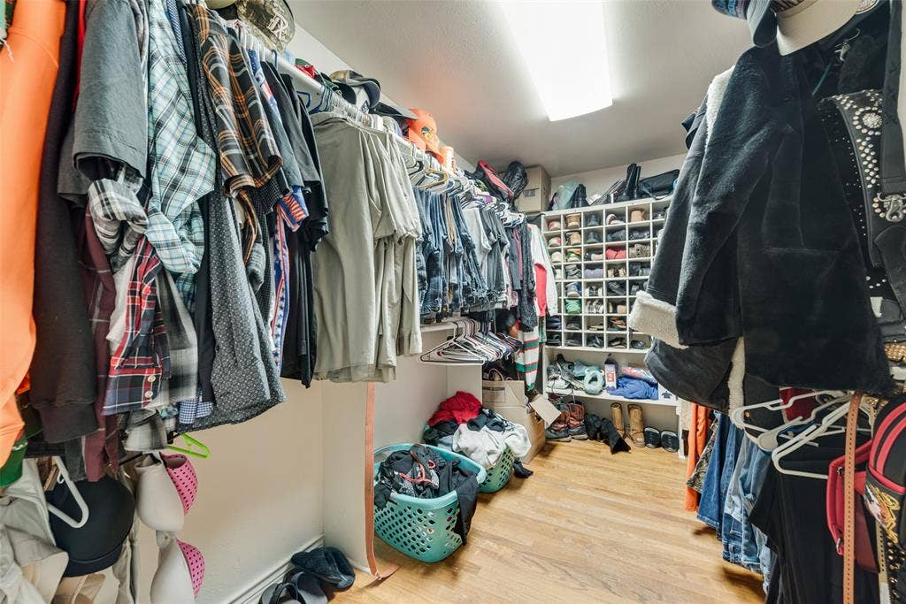 Walk-in closet featuring wood-finish flooring, built-in shelving, and tiered hanging rods