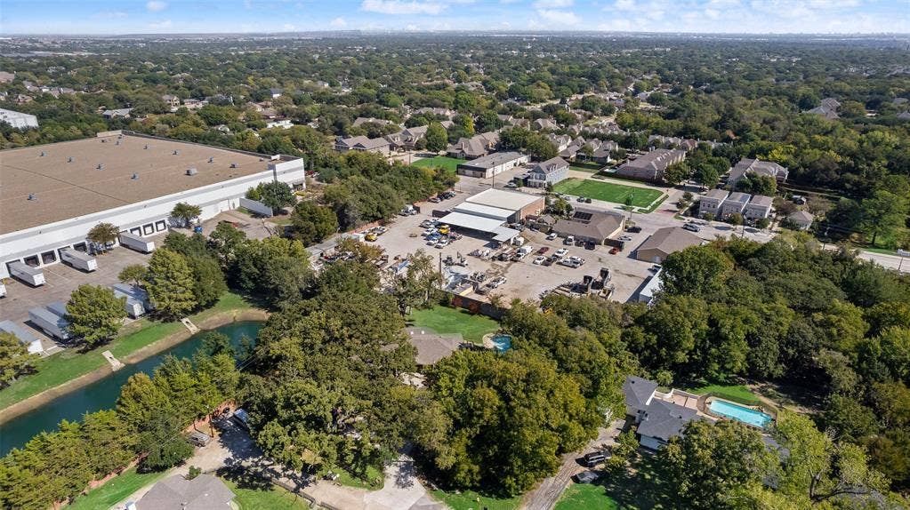 Aerial perspective of property featuring a private swimming pool, winding water feature, mature tree canopy, and dense surrounding greenery