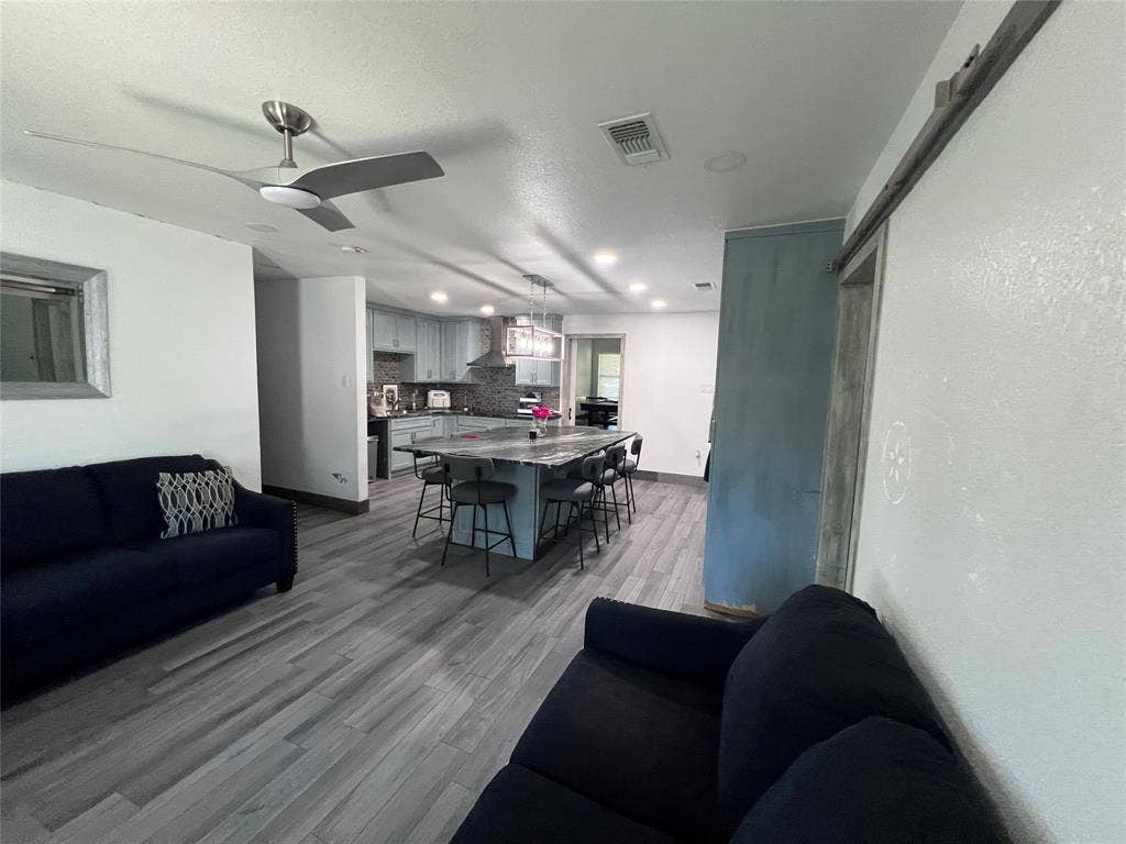 201 Darien Drive, Mesquite, TX 75149 Wood-finish flooring throughout, kitchen featuring a central island with stone countertop, stainless steel range hood, recessed lighting, and sliding barn door hardware
