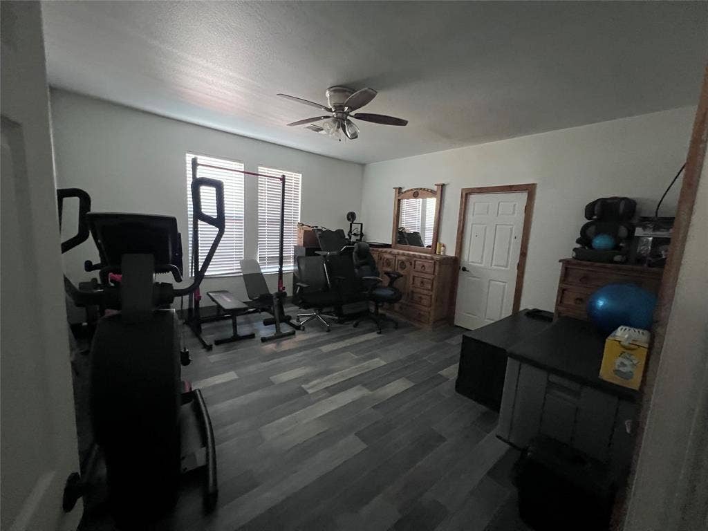 201 Darien Drive, Mesquite, TX 75149 Room featuring multi-tone wood-finish flooring, dual windows with integrated blinds, and a ceiling-mounted light fixture with fan blades