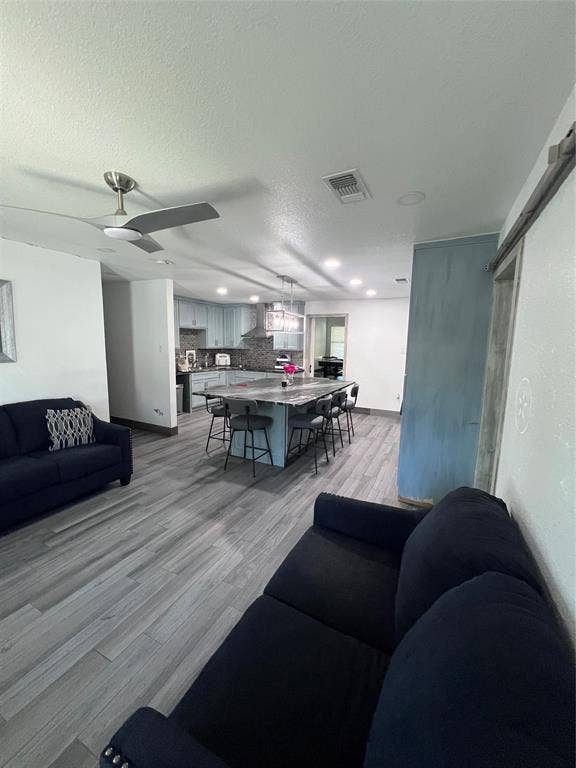 201 Darien Drive, Mesquite, TX 75149 Open-concept kitchen featuring an expansive center island with stone-finish countertop, stainless steel range hood, recessed lighting, and wood-finish flooring