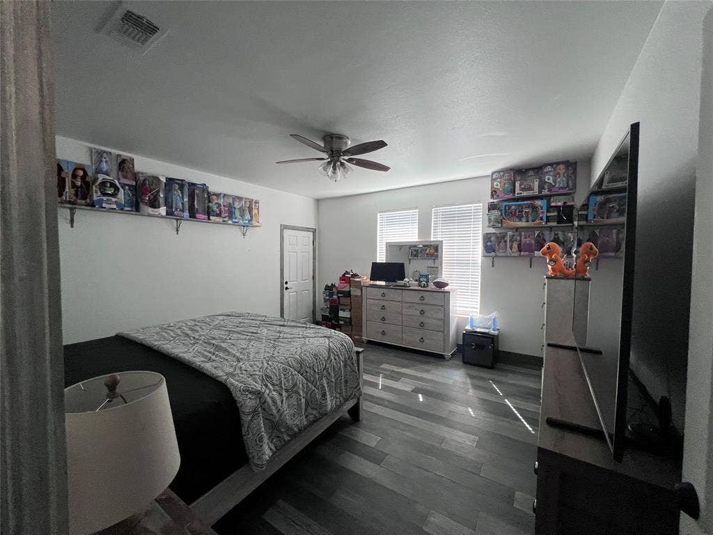 201 Darien Drive, Mesquite, TX 75149 Room featuring wood-finish flooring, a ceiling fan with integrated lighting, dual windows with horizontal blinds, and two wall-mounted storage shelves