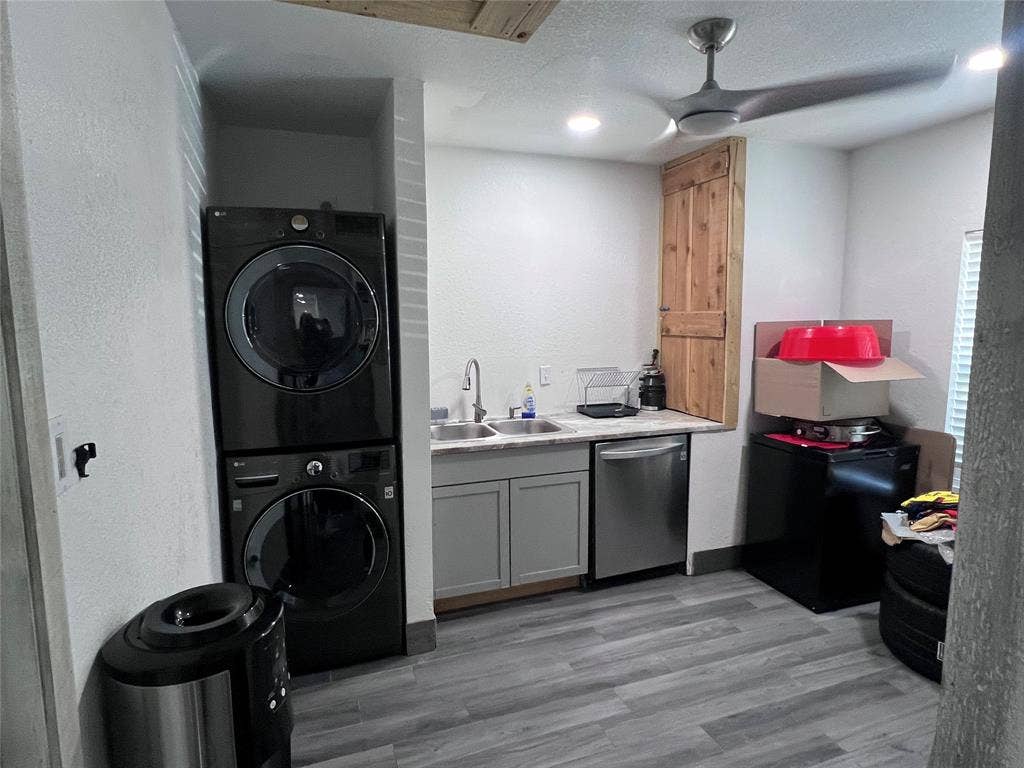 201 Darien Drive, Mesquite, TX 75149 Utility area featuring wood-finish flooring, shaker-style cabinetry, stainless steel sink with pull-down faucet, and built-in wood-paneled storage