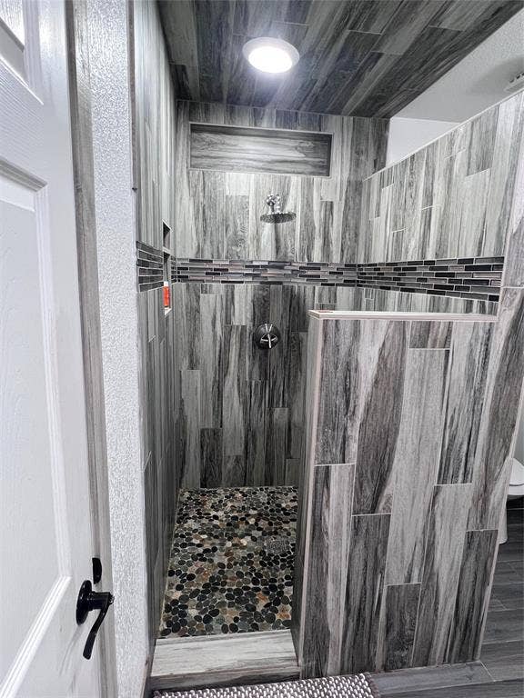 201 Darien Drive, Mesquite, TX 75149 Walk-in shower featuring wood-finish tile wall cladding, a decorative glass mosaic tile accent border, recessed wall niche, and natural stone pebble floor tiling