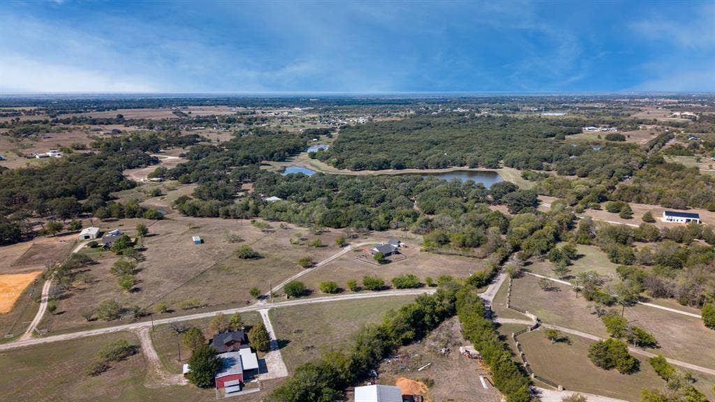 8935 Bluebonnet Drive, Scurry, TX 75158 Aerial perspective of rural acreage featuring rolling pastures, dense tree lines, and multiple water features