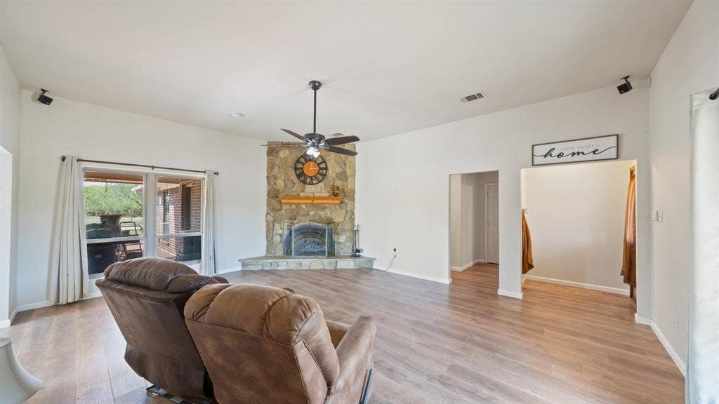 8935 Bluebonnet Drive, Scurry, TX 75158 High ceilings featuring a central fan, stone-surround fireplace with a hearth, and wood-finish flooring