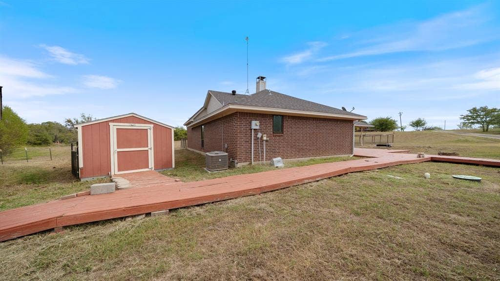 8935 Bluebonnet Drive, Scurry, TX 75158 Brick exterior, detached storage shed, and wraparound wood decking