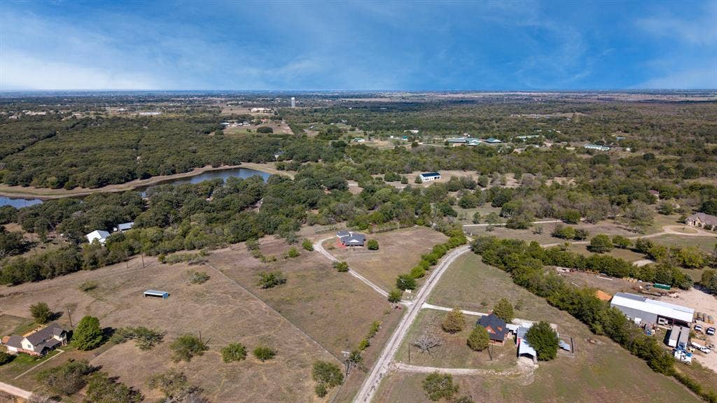 8935 Bluebonnet Drive, Scurry, TX 75158 Aerial view of extensive acreage featuring mature trees, open pastureland, and a natural pond