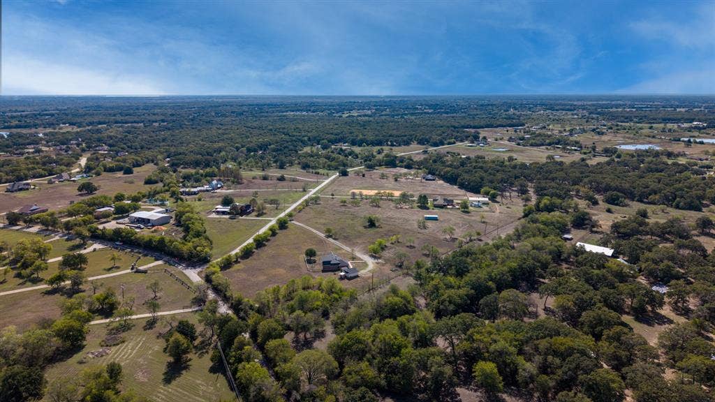 8935 Bluebonnet Drive, Scurry, TX 75158 Aerial perspective of expansive acreage featuring mature tree clusters, open pasture land, and established gravel road access