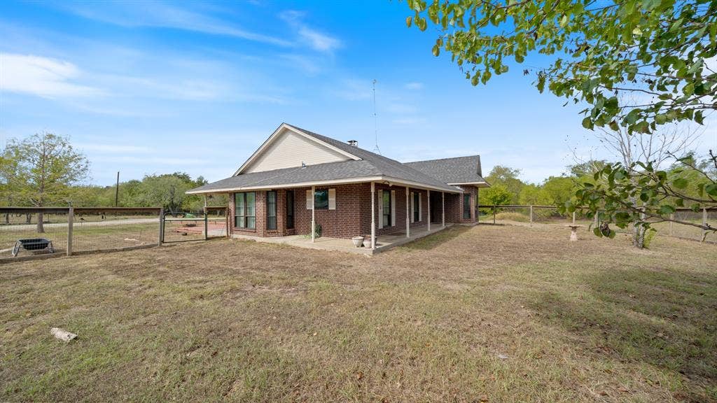 8935 Bluebonnet Drive, Scurry, TX 75158 Single-story brick exterior featuring a wrap-around covered porch, gabled roofline, and post-and-rail perimeter fencing