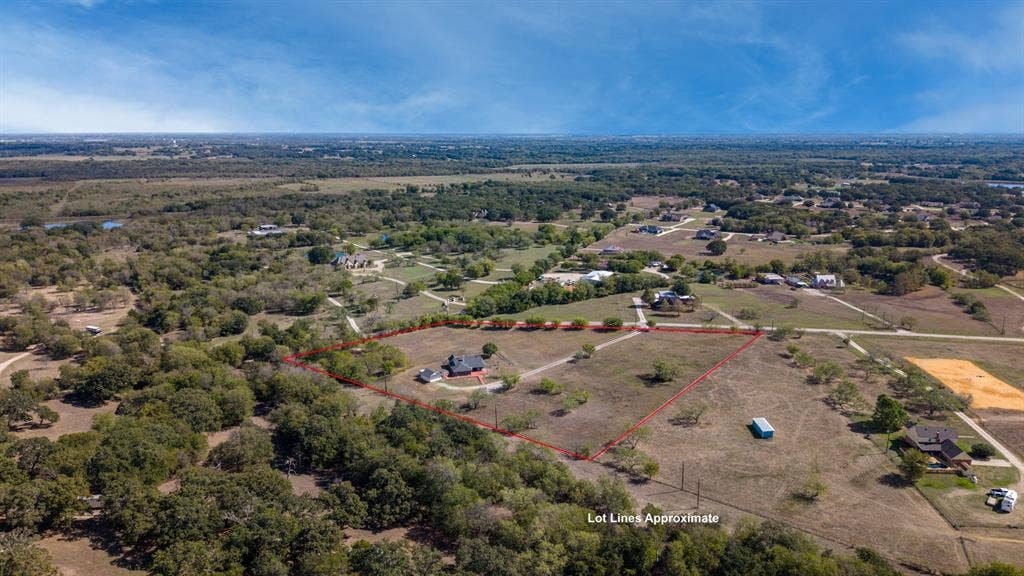 8935 Bluebonnet Drive, Scurry, TX 75158 Aerial perspective of a large acreage lot featuring expansive open grass fields, mature trees, and a residential structure