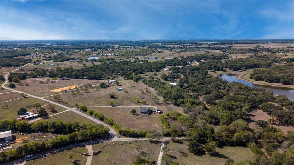 8935 Bluebonnet Drive, Scurry, TX 75158 Aerial view of acreage featuring mature tree lines, open pasture, and a water feature