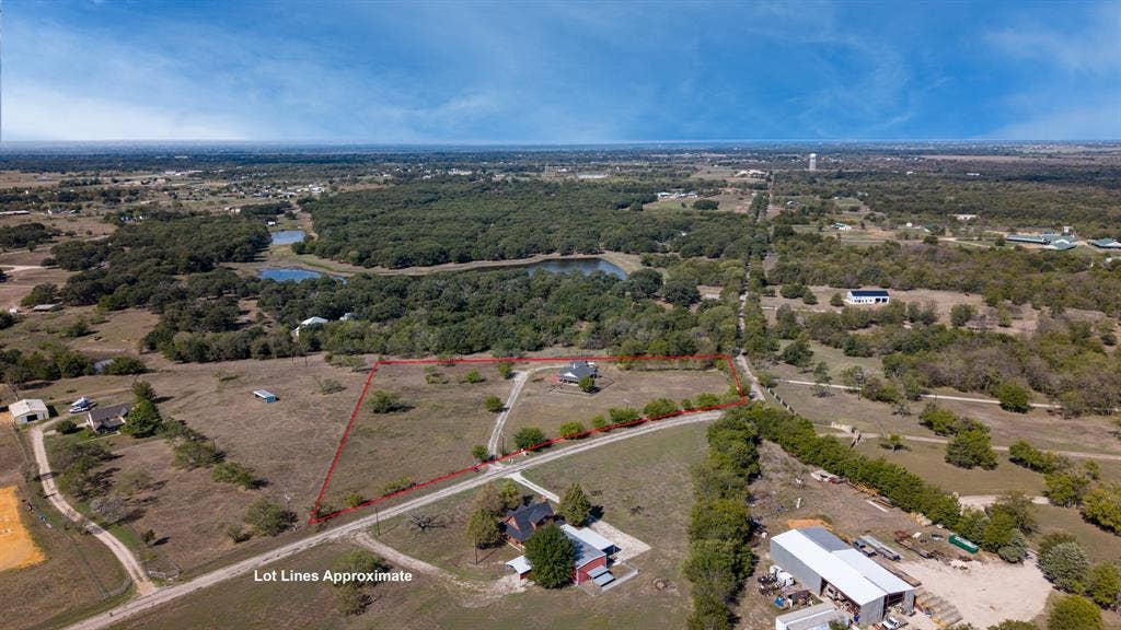 8935 Bluebonnet Drive, Scurry, TX 75158 Expansive acreage featuring cleared land, mature trees, a long gravel driveway, and a fenced perimeter