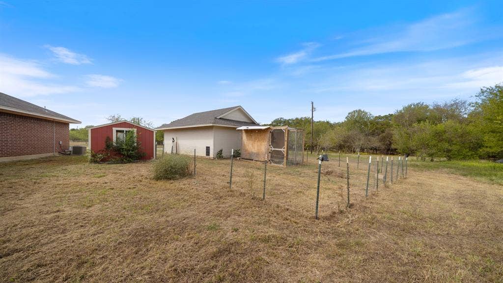 8935 Bluebonnet Drive, Scurry, TX 75158 Expansive yard featuring a red storage structure, detached garage, and fenced enclosure