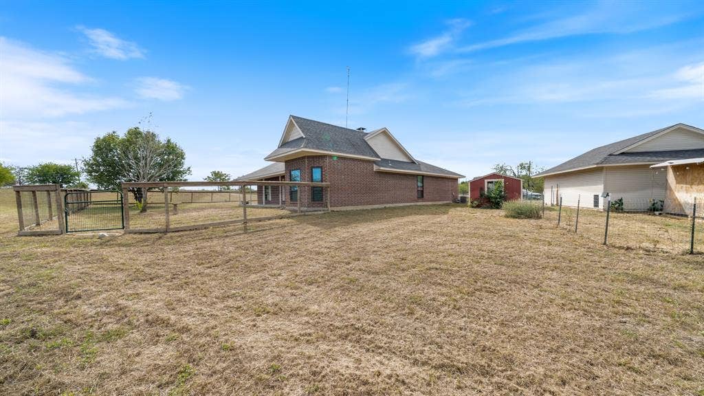 8935 Bluebonnet Drive, Scurry, TX 75158 Brick exterior home featuring a fenced outdoor perimeter, gable rooflines, and an accessory storage structure