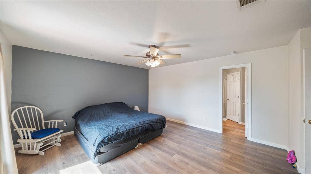 8935 Bluebonnet Drive, Scurry, TX 75158 Room featuring wood-finish flooring, a neutral color palette with a slate-toned accent wall, and a multi-light ceiling fan