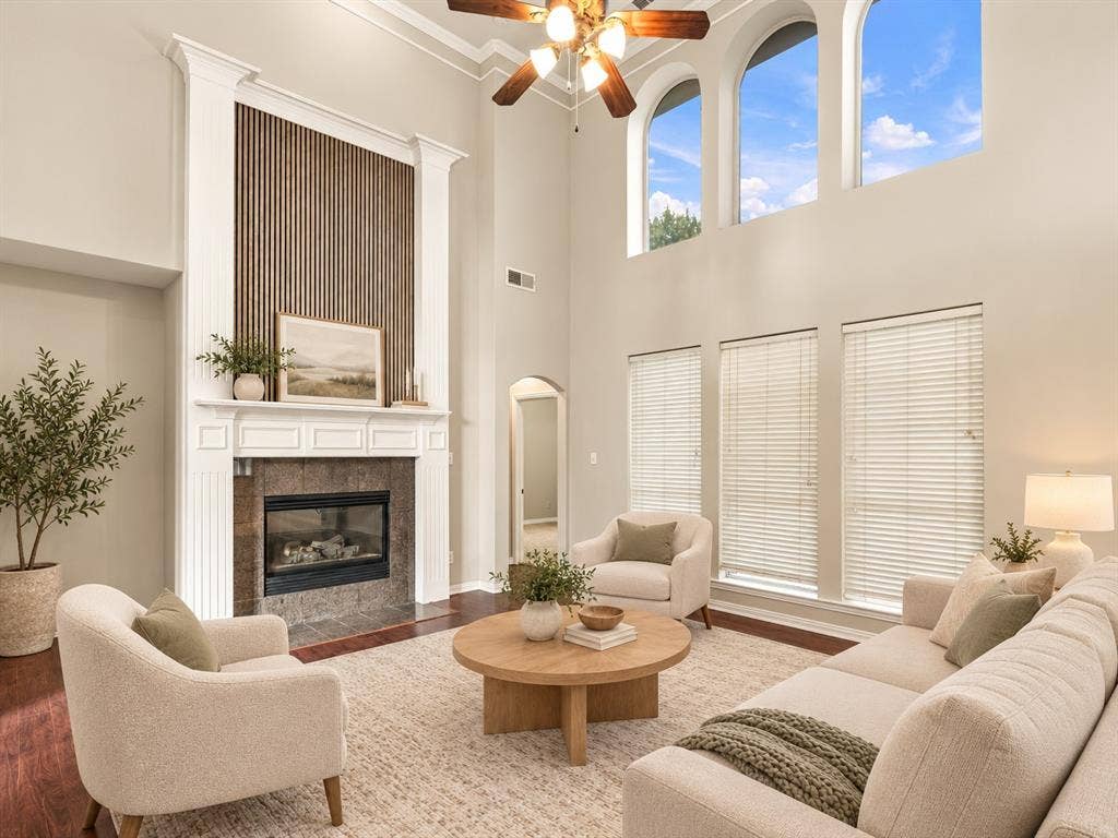 Double-height ceiling, floor-to-ceiling fireplace with wood-slat detailing, arched clerestory windows, and wood-finish flooring